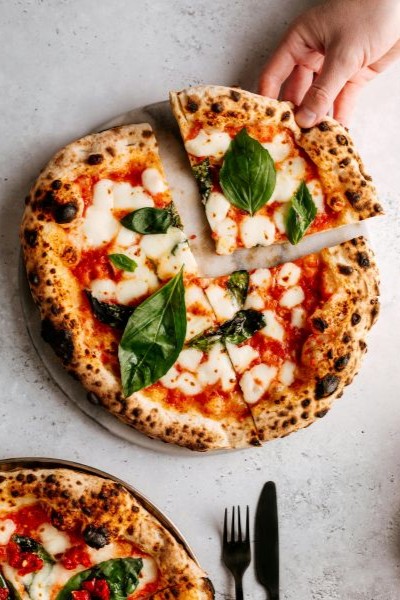 Hand holding slice of pizza